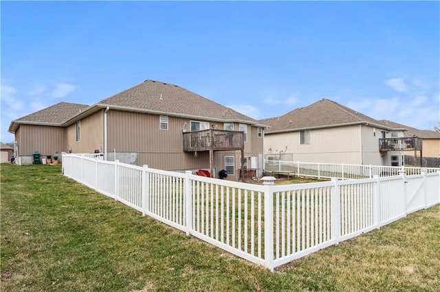 back of house featuring a fenced backyard, a balcony, a shingled roof, and a yard