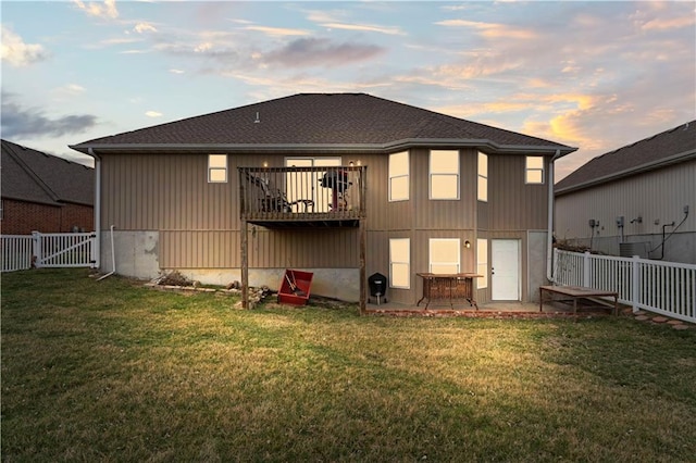 back of house at dusk with a yard, a patio area, a fenced backyard, and a gate