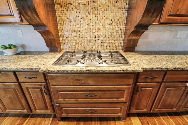 kitchen with backsplash, light stone countertops, light hardwood / wood-style floors, and stainless steel gas stovetop