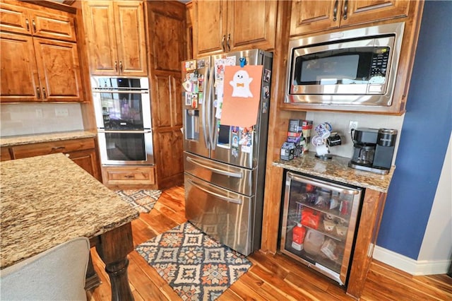 kitchen featuring light stone countertops, stainless steel appliances, beverage cooler, and dark wood-type flooring