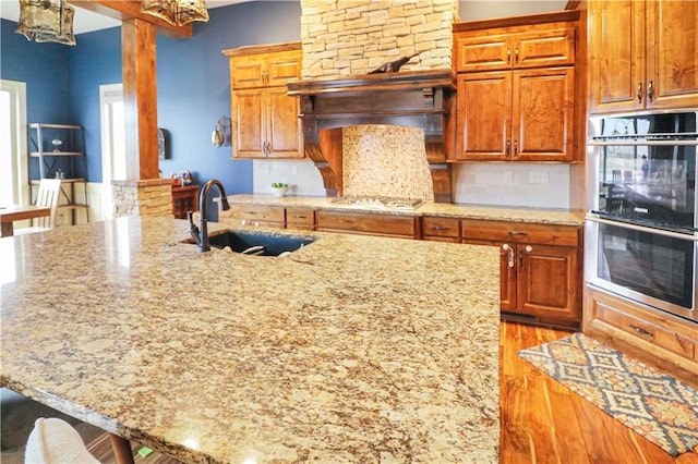 kitchen featuring light stone countertops, sink, a kitchen breakfast bar, light hardwood / wood-style floors, and appliances with stainless steel finishes