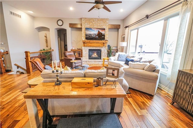 living room with ceiling fan, light wood-type flooring, a fireplace, and radiator