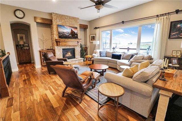 living room with a stone fireplace, ceiling fan, and hardwood / wood-style floors