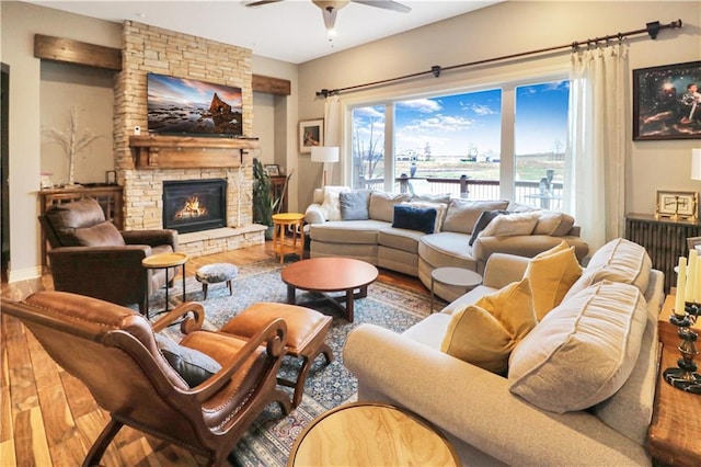 living room featuring hardwood / wood-style flooring, a stone fireplace, and ceiling fan