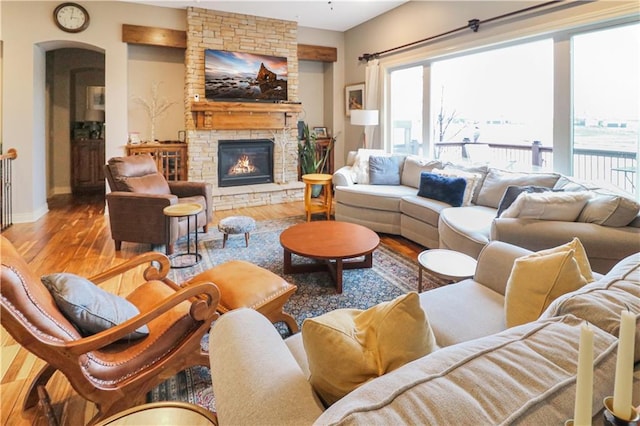 living room with a stone fireplace and hardwood / wood-style flooring