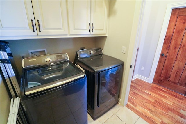 laundry area with cabinets, light hardwood / wood-style floors, and washing machine and clothes dryer