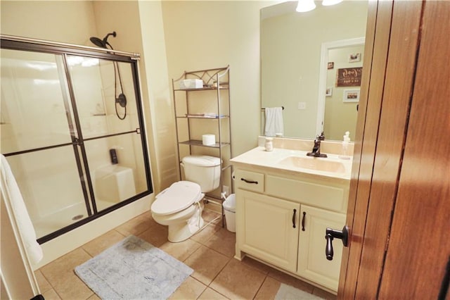 bathroom with tile patterned flooring, vanity, toilet, and a shower with shower door