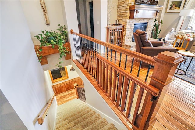 stairway featuring a stone fireplace and wood-type flooring