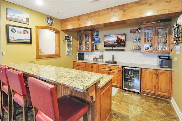 bar with light stone countertops, sink, and beverage cooler