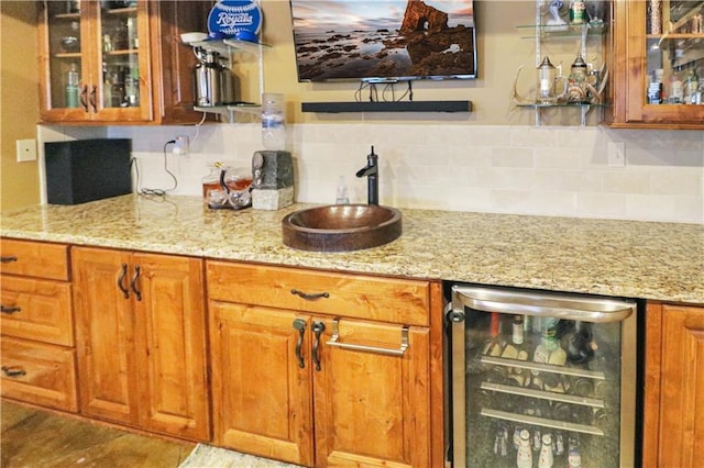 bar with light stone counters, sink, beverage cooler, and tasteful backsplash