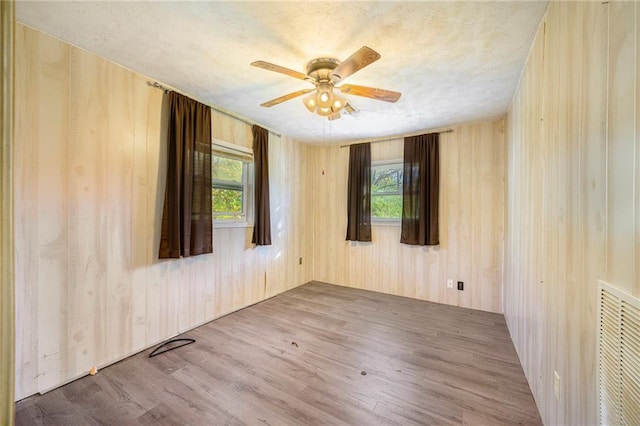 spare room featuring ceiling fan, a healthy amount of sunlight, and wood-type flooring