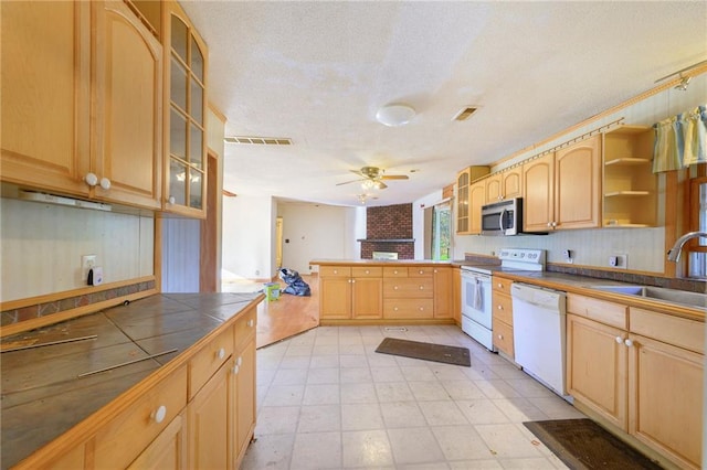 kitchen with kitchen peninsula, white appliances, ceiling fan, sink, and tile counters