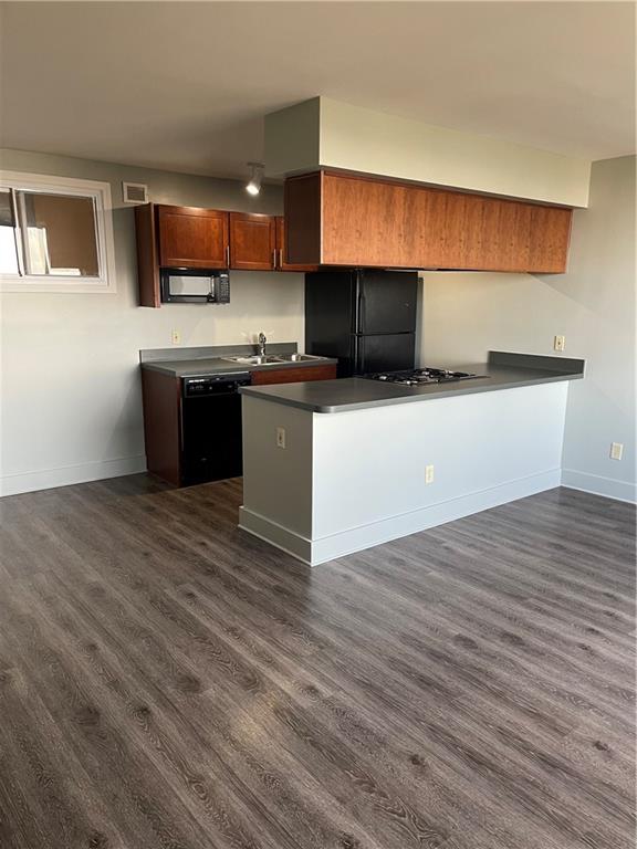 kitchen with black appliances, sink, kitchen peninsula, and dark wood-type flooring