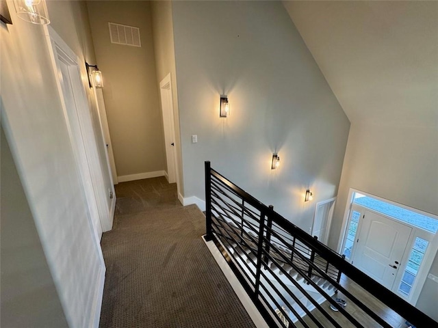 hall with dark carpet and high vaulted ceiling