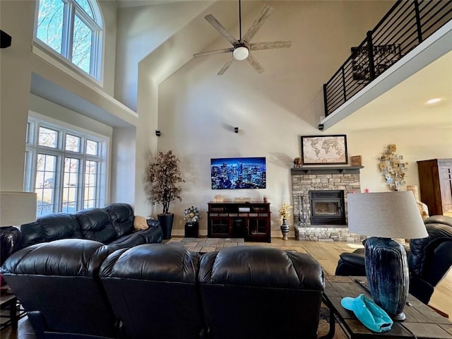 living room featuring a fireplace, plenty of natural light, wood-type flooring, and a high ceiling