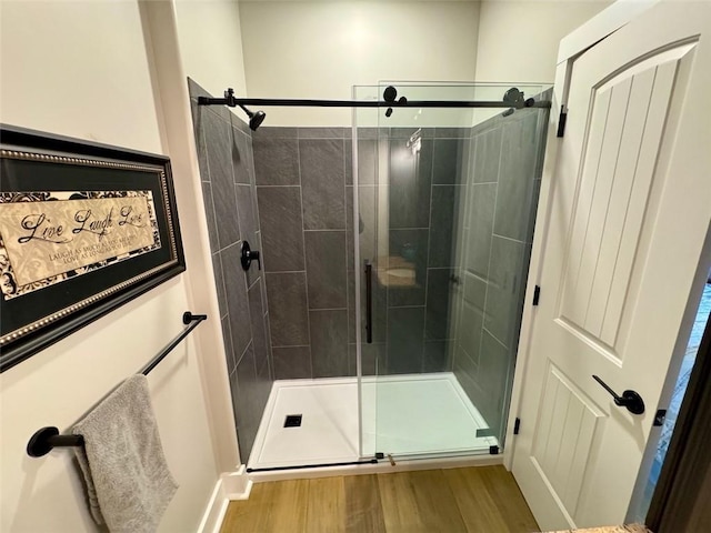 bathroom with hardwood / wood-style flooring and a shower with shower door