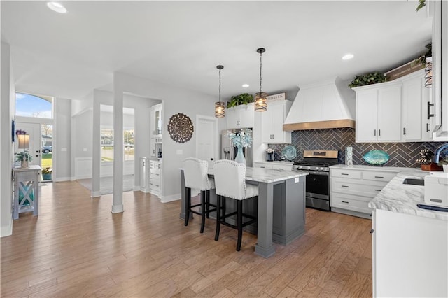 kitchen featuring custom range hood, stainless steel appliances, a kitchen island, and white cabinetry