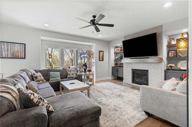 living room featuring ceiling fan, light hardwood / wood-style floors, and a fireplace