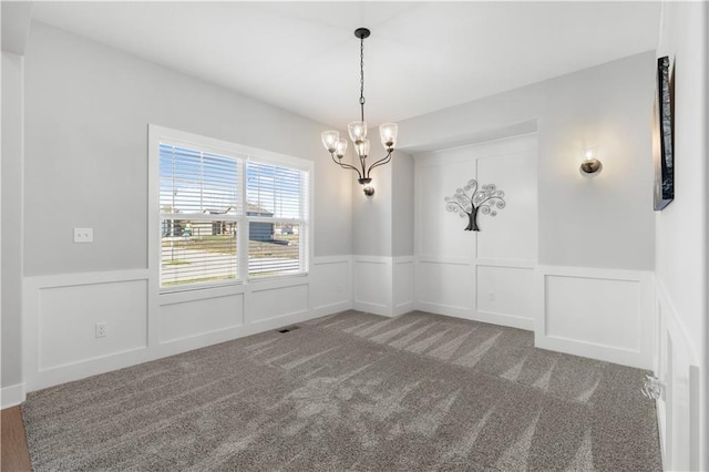 spare room featuring carpet flooring and a chandelier