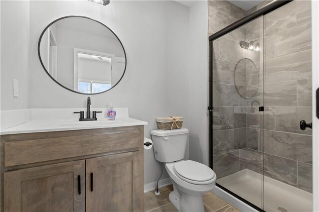 bathroom with tile patterned floors, vanity, toilet, and a shower with door