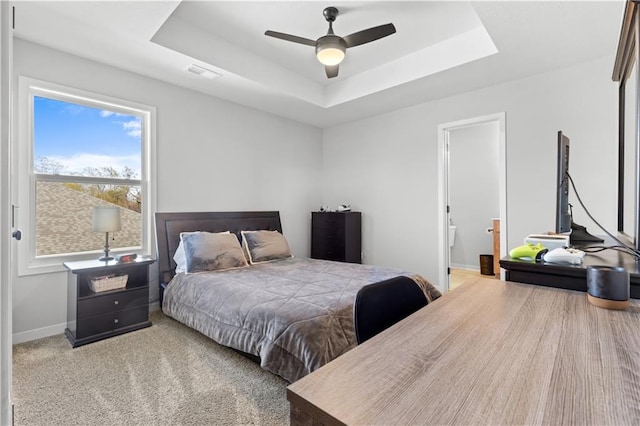 bedroom featuring ceiling fan, a raised ceiling, carpet floors, and ensuite bath