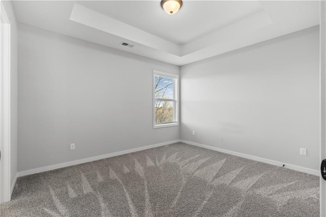 carpeted spare room with a raised ceiling