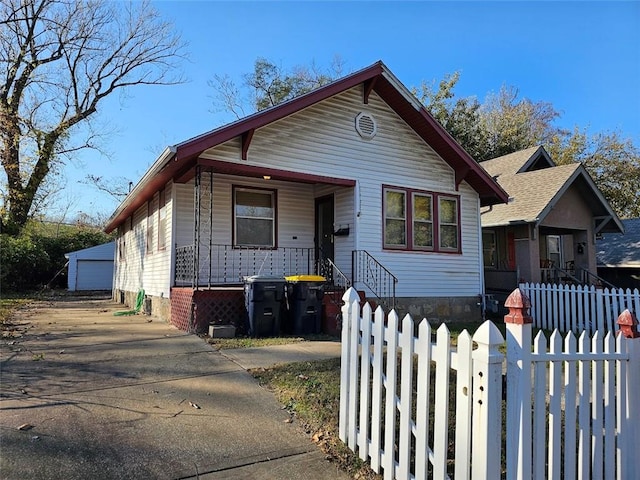 bungalow-style house with a porch, a garage, and an outbuilding