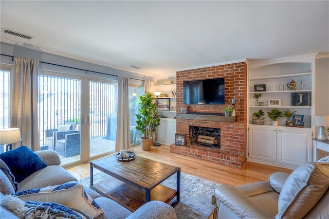 living room featuring plenty of natural light, built in shelves, a fireplace, and light hardwood / wood-style flooring