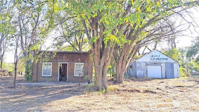 207 E 4th, Longton, KS 67352 - view of front of house featuring a garage, brick siding, and an outbuilding