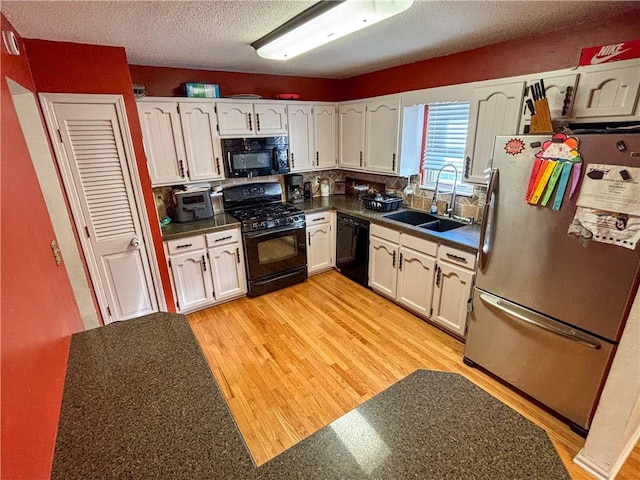 kitchen with a textured ceiling, sink, black appliances, light hardwood / wood-style floors, and white cabinetry