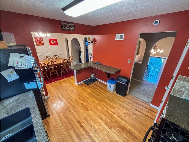 recreation room featuring a textured ceiling, hardwood / wood-style flooring, and an inviting chandelier