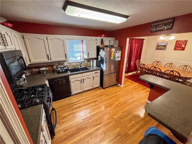 kitchen with black appliances, light hardwood / wood-style floors, white cabinetry, and sink