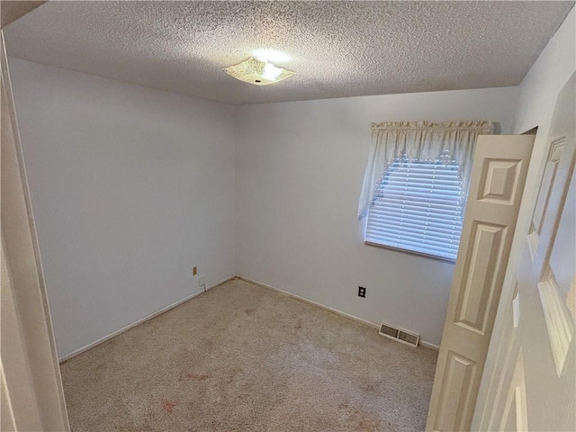 spare room with light colored carpet and a textured ceiling