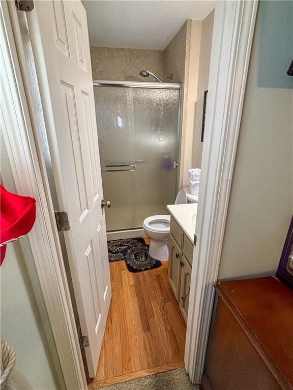 bathroom with hardwood / wood-style flooring, vanity, toilet, and a shower with shower door