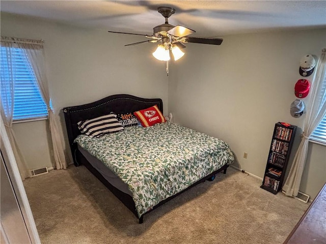 bedroom with multiple windows, ceiling fan, and carpet floors