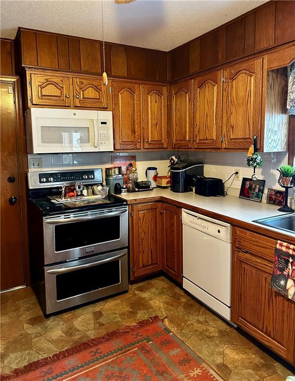 kitchen with sink, white appliances, and a textured ceiling