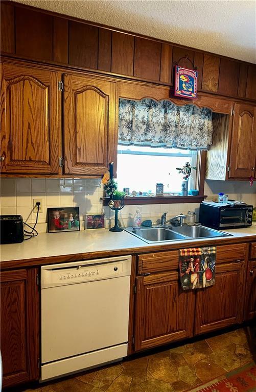 kitchen with sink, a textured ceiling, dishwasher, and tasteful backsplash