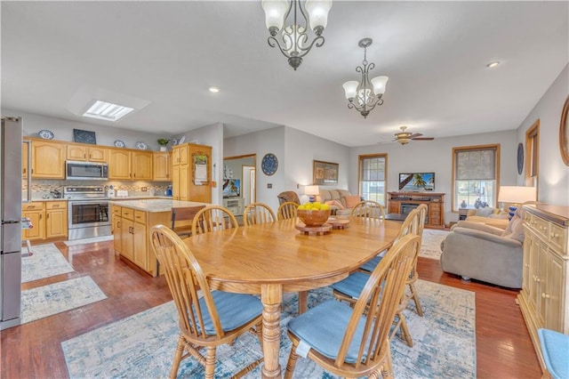 dining area featuring ceiling fan with notable chandelier and light wood-type flooring