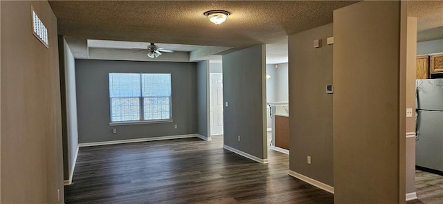 unfurnished room with a textured ceiling, ceiling fan, and dark wood-type flooring