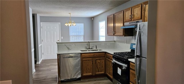 kitchen featuring sink, dark wood-type flooring, stainless steel appliances, a notable chandelier, and decorative light fixtures