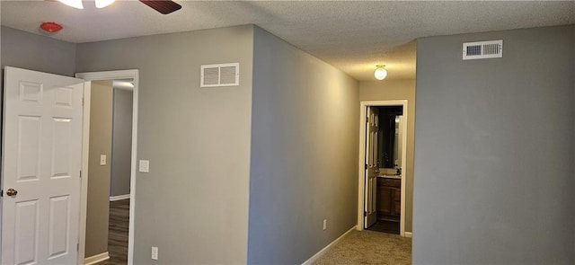 hall featuring carpet and a textured ceiling