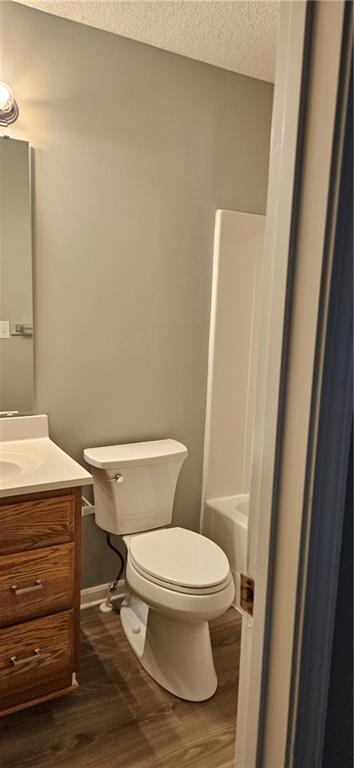 bathroom featuring toilet, vanity, a textured ceiling, and hardwood / wood-style flooring