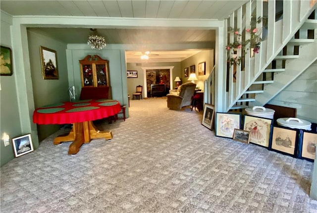 dining space with carpet flooring, beam ceiling, ceiling fan with notable chandelier, and wooden ceiling