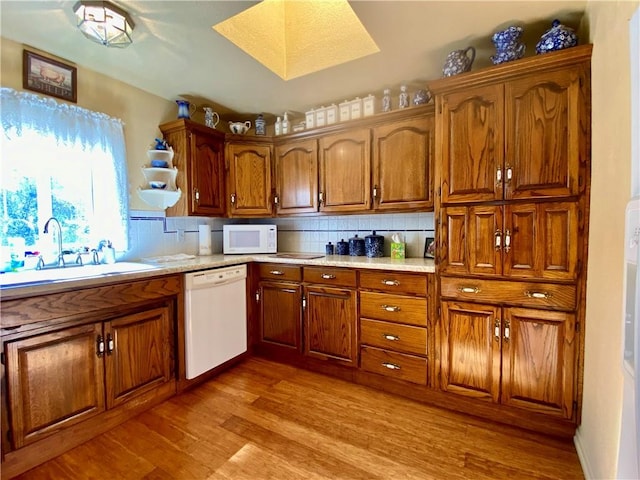 kitchen featuring decorative backsplash, white appliances, sink, and light hardwood / wood-style flooring