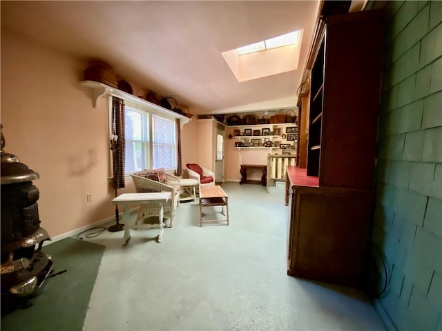 sitting room featuring vaulted ceiling with skylight and concrete floors