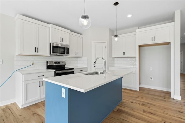 kitchen with pendant lighting, sink, a kitchen island with sink, appliances with stainless steel finishes, and white cabinets