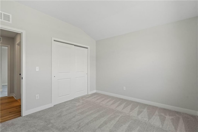 unfurnished bedroom with carpet floors, a closet, and lofted ceiling