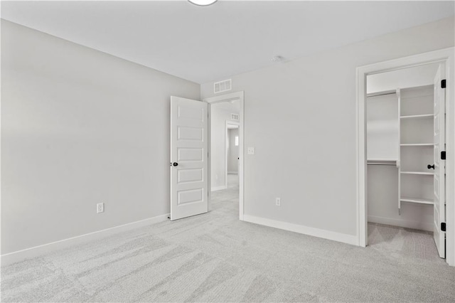 unfurnished bedroom featuring a spacious closet, a closet, and light colored carpet