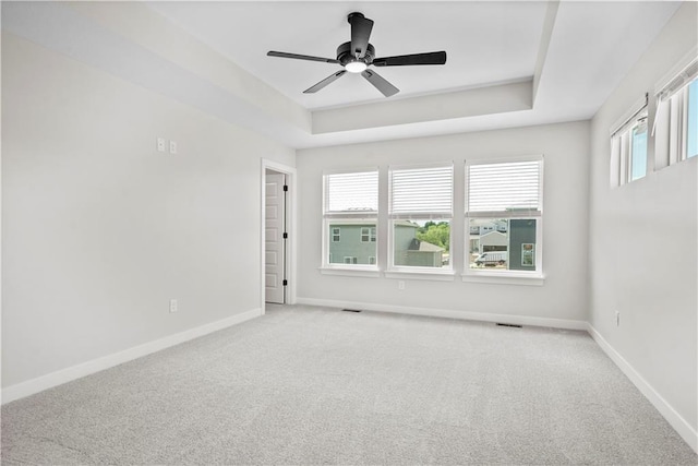 spare room with light colored carpet, ceiling fan, and a tray ceiling