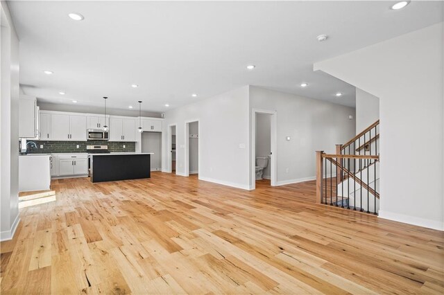 1933 SW Merryman Dr, Lees Summit, MO 64082 - unfurnished living room featuring light wood-style floors, recessed lighting, baseboards, and stairway